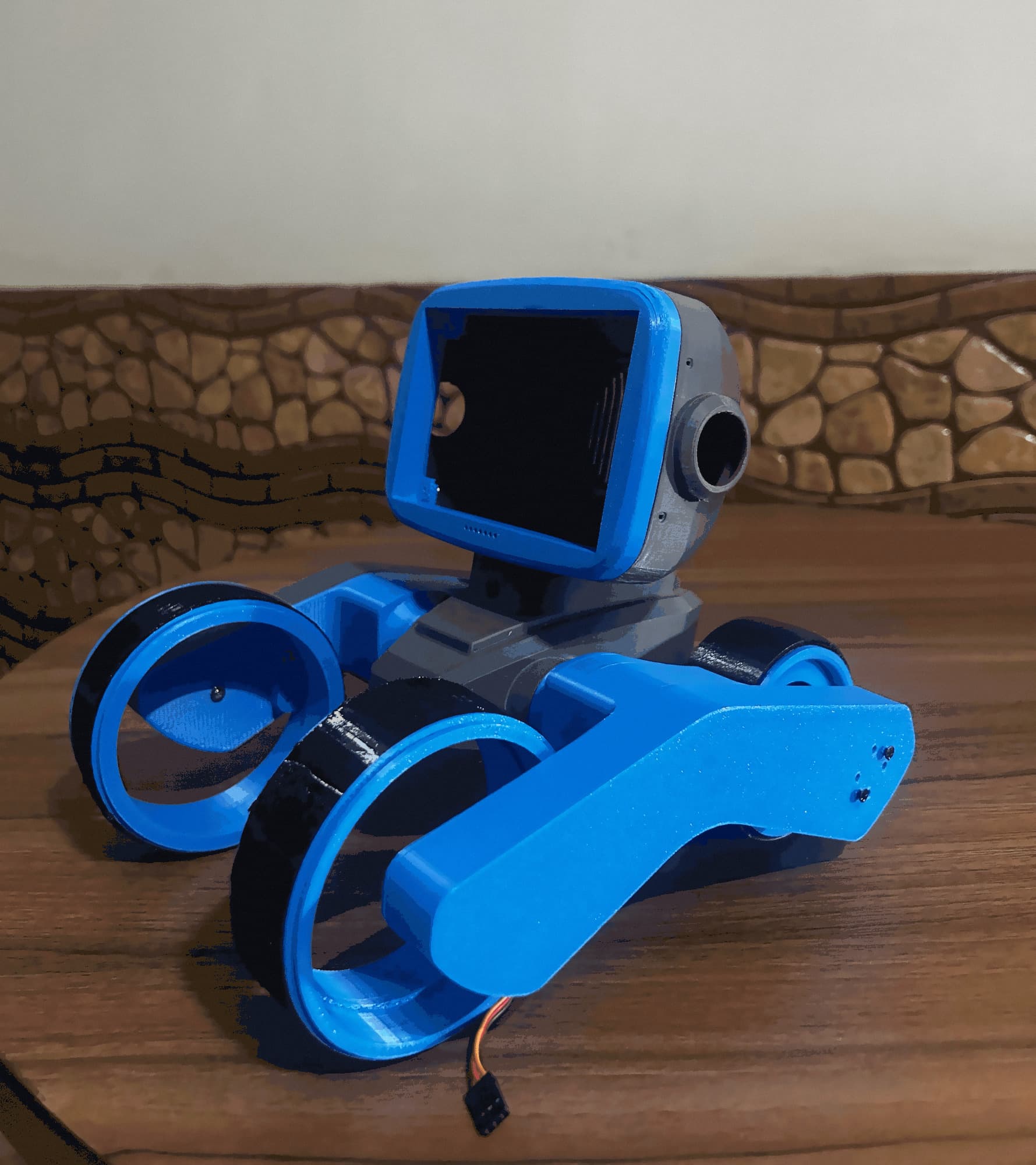 The first assembled Pracii prototype, blue and grey 3D-printed parts, on a wooden table